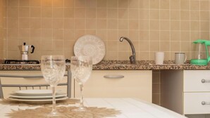 A kitchen with a dining table set for two, a coffee maker, a kettle, and a decorative plate. - The Ancient Sailing Ship - Alghero (Alghero)