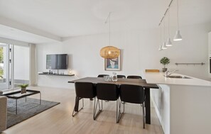 Una cocina moderna con comedor, televisor montado en la pared y un ventanal grande.