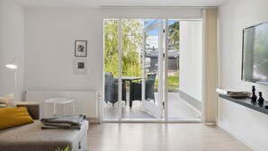 Ein modernes Wohnzimmer mit einer Couch, einem kleinen runden Tisch und einem Fernseher an der Wand.