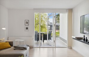 Ein modernes Wohnzimmer mit einer Couch, einem kleinen runden Tisch und einem Fernseher an der Wand.