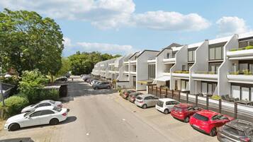 A row of modern apartment buildings with a parking lot in front.