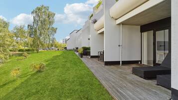 A modern building with a flat roof, a covered outdoor area with furniture, and a well-maintained lawn.