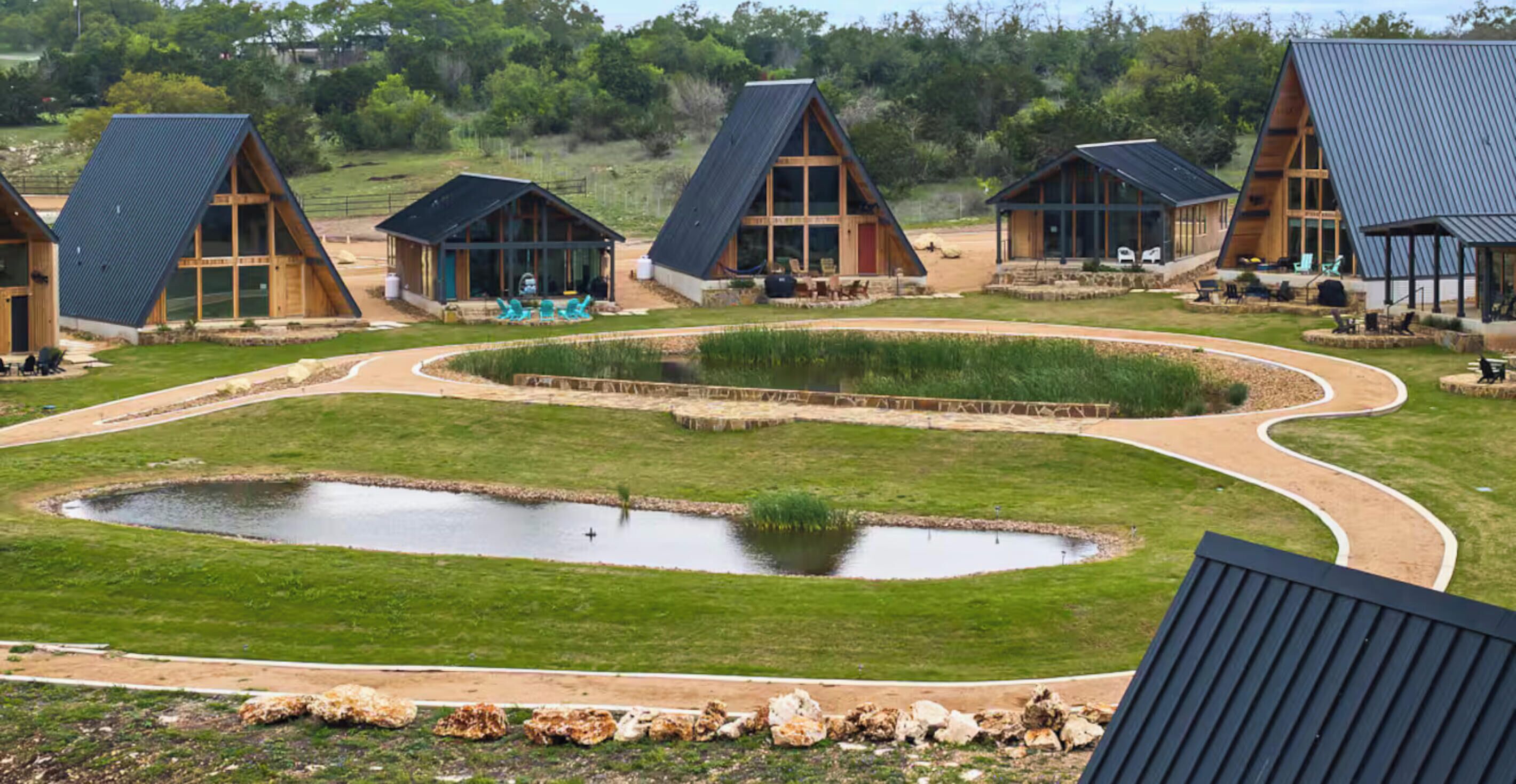 A series of A-frame cabins with a central pond and surrounding pathways.