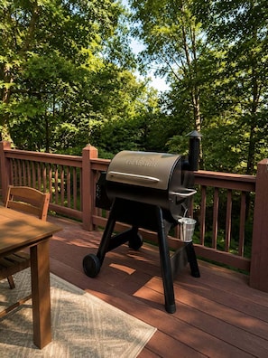 A barbecue grill on a wooden deck with a table and chairs. - 5BR Mass Resort | Movie Lounge +Pool/Poker Table+Arcade+Gym+Remote Workstatio... (McGaheysville)