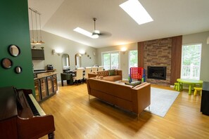 Ein geräumiges Wohnzimmer mit Klavier, Kamin und Essbereich mit Stühlen und Tisch.