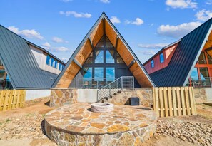 A modern building with a central atrium, stone flooring, and a staircase leading to the upper levels. - A-Frame Cabin | Community Ponds | Fire Pit (New Braunfels)