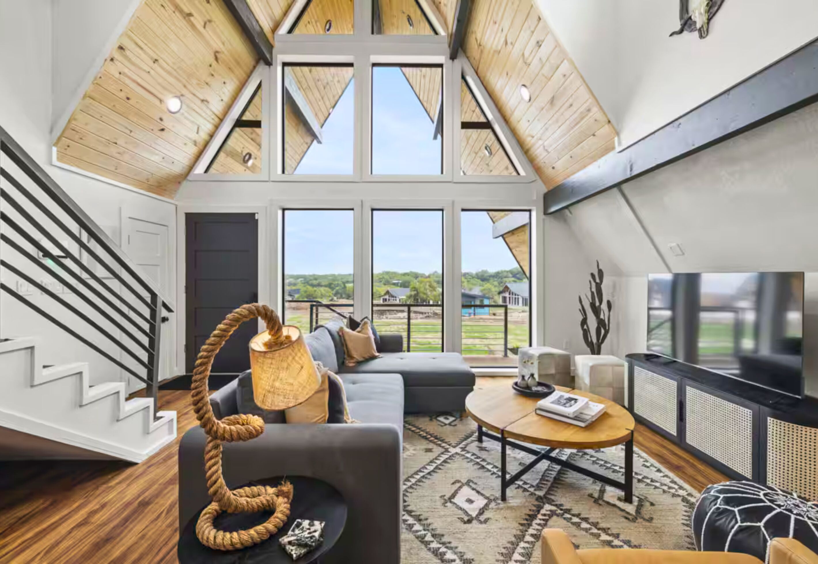 Un loft espacioso con techo alto, ventanas grandes, una escalera y un rincón de descanso acogedor con alfombra.