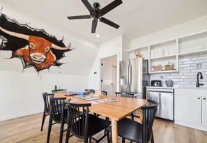 Eine moderne Küche mit weißen Schränken, einem Edelstahlkühlschrank und einem Deckenventilator.