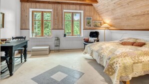 Une chambre à coucher avec un grand lit, un bureau et deux fenêtres à cadres en bois.