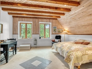 Ein Schlafzimmer mit einem großen Bett, einem Schreibtisch und zwei Fenstern mit Holzrahmen.