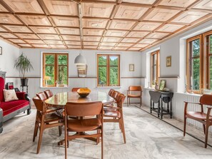 Un comedor amplio con techo de madera, ventanas grandes y vistas a zonas verdes.