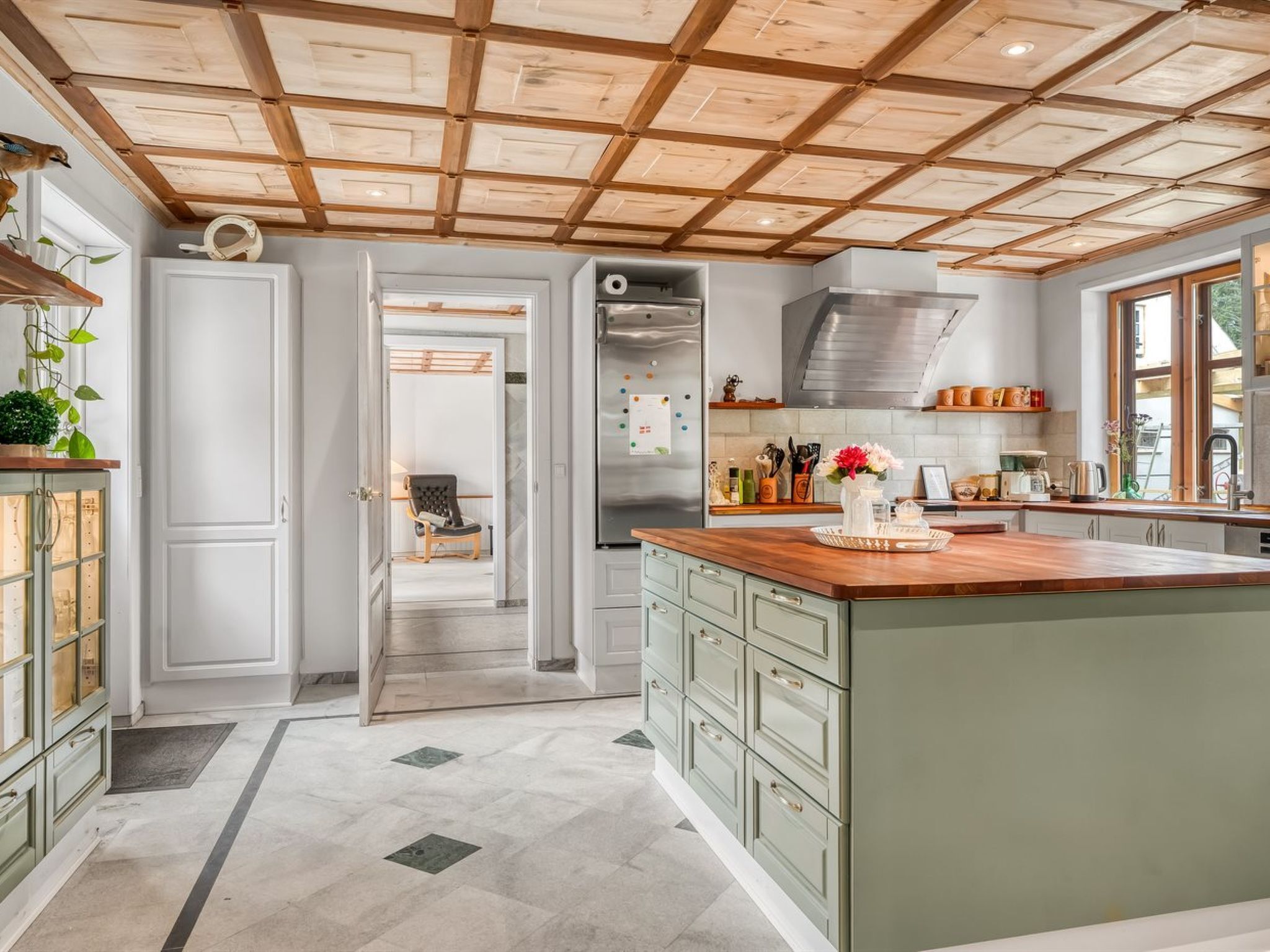 A kitchen with a large island, wooden ceiling, and a view to the dining area.
