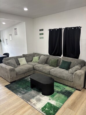 A living room with a sectional sofa, a coffee table, and a patterned rug.