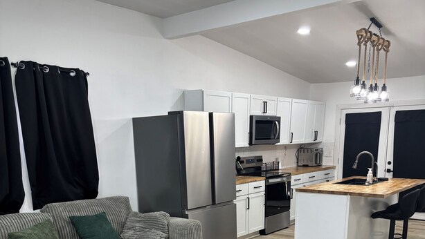 A modern living room with a sofa, coffee table, and a kitchen area with appliances.
