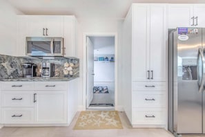 A modern kitchen with white cabinetry, a built-in microwave, and a stainless steel refrigerator. - Private Waterfront Getaway in Englewood on Lemon Bay: Just 4 Miles to Gulf Coast Beaches! (Englewood)