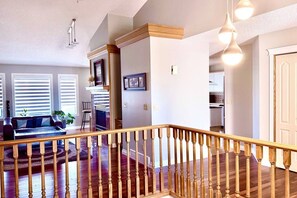 A spacious living area with a wooden staircase, a fireplace, and a view of the kitchen. - Luxury home in Calgary NW (Calgary)