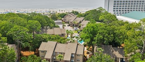 Zona residencial con edificios de varios pisos, piscina y playa al fondo.