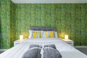 Ein Schlafzimmer mit Bett, Nachttischen und einer Wand mit grüner Bambuspapier.