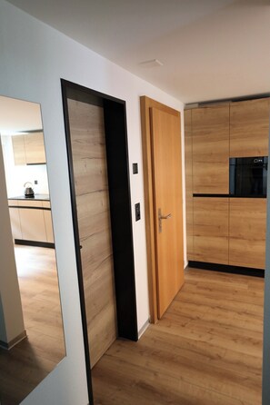 A modern kitchen with wooden cabinets and a black appliance. - Mornings & Refined Alpine Living 1098 (Wallis)