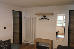 A room with a radiator, a wooden bench, a coat rack, and a mirror on the wall. - Mornings & Refined Alpine Living 1098 (Wallis)