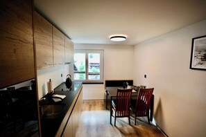 A compact kitchen with a black countertop, wooden cabinets, and a window providing natural light. - Mornings & Refined Alpine Living 1098 (Wallis)