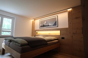 A bedroom with a bed, a window, and a framed picture on the wall. - Mornings & Refined Alpine Living 1098 (Wallis)