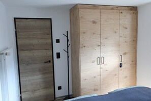 A bedroom with a large wooden wardrobe, a door, and a bed. - Alpine Calm with Unforgettable Views 1099 (Wallis)