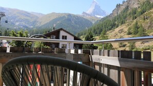 Blick auf Berge mit Chalet und Stuhl im Vordergrund.