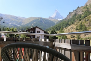 A mountain view with a chalet and a chair in the foreground. - Alpine Calm with Unforgettable Views 1099 (Wallis)
