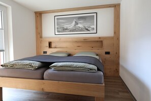 Ein Bett mit einem Holz-Kopfteil, ein gerahmtes Bild darüber und ein Fenster links.