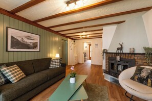 Ein gemütliches Wohnzimmer mit einer Couch, einem kleinen Tisch mit Pflanze, einem Kamin und einem Wandbild.