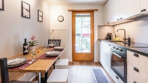 Una cocina compacta con zona de comedor, que incluye una mesa de madera, sillas, un reloj y una ventana con vistas.