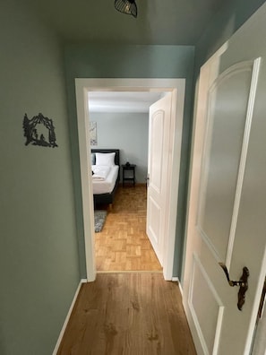 A hallway leading to a bedroom with a bed, a nightstand, and a door. - A Luxurious Retreat Above Zermatt 1100 (Wallis)