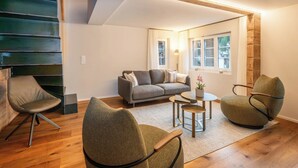 Un salon moderne comprenant un canapé, deux fauteuils, une table basse et une lampe.