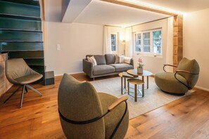 Ein stilvolles Wohnzimmer mit einer Couch, zwei Sesseln, einem Couchtisch und einer Lampe.