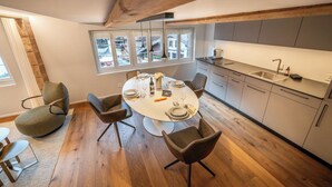 Une cuisine moderne avec un coin repas, un plancher en bois et une vue par les fenêtres.