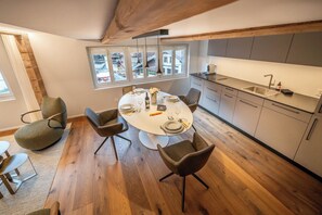 Eine moderne Küche mit Essbereich, Holzboden und Blick durch die Fenster.