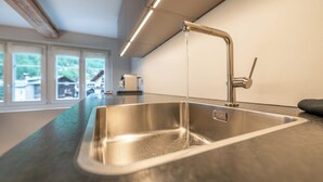 Une cuisine moderne dotée d’un évier en acier inoxydable, d’un robinet et d’un plan de travail.