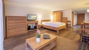 Et hotelværelse med en seng, et træskrivebord, et fjernsyn og et klædeskab.