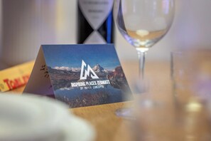 Un folleto con el título 'Inspiring Places Zermatt' de Mayer Concepts sobre una mesa con una copa de vino.