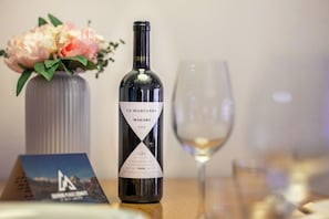 A bottle of wine with a label, a glass, and a vase with flowers on a table. - Wake, Wander & Unwind in Alpine Luxury 1102 (Wallis)