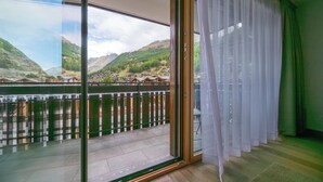 Et værelse med en stor skydedør, der fører ud til en balkon med udsigt over et bjergrigt landskab.