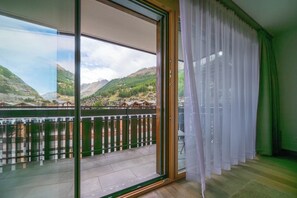 A room with a large sliding glass door leading to a balcony with a view of a mountainous landscape. - Magic & Contemporary Alpine Comfort 1103 (Wallis)