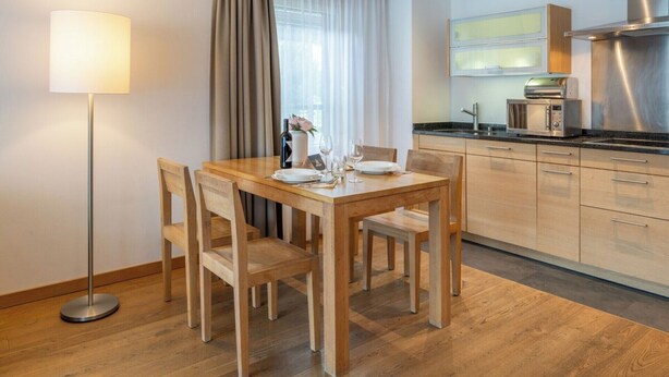 Et moderne køkken med rustfrie stålgadgetter, et spiseområde med træmøbler og en gulvlampe.