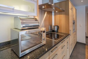 A modern kitchen with a built-in toaster, a coffee maker, and a stove. - Magic & Contemporary Alpine Comfort 1103 (Wallis)