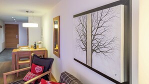 A living room with a sofa, a dining table, and a large framed artwork on the wall. - A Serene Luxury Escape in the Swiss Alps 1104 (Wallis)