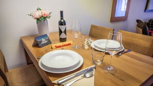 A dining table set with plates, cutlery, a wine bottle, glasses, and a flower vase. - A Serene Luxury Escape in the Swiss Alps 1104 (Wallis)