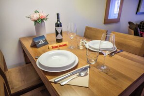 A dining table set with plates, cutlery, a wine bottle, glasses, and a flower vase. - A Serene Luxury Escape in the Swiss Alps 1104 (Wallis)