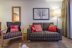 A living room with a sofa, armchair, and a framed picture on the wall. - A Serene Luxury Escape in the Swiss Alps 1104 (Wallis)