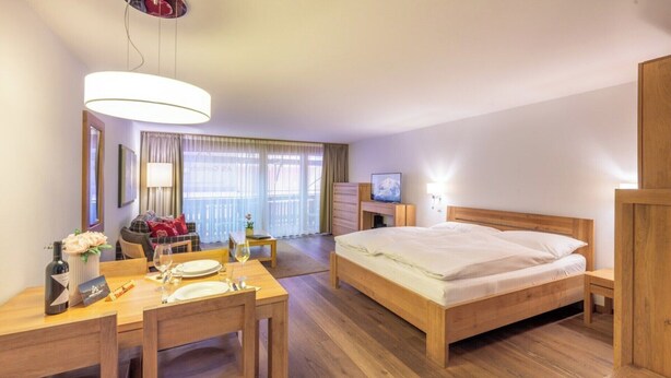 A hotel room with a bed, a desk with a chair, a television, and a window with curtains. - A Serene Luxury Escape in the Swiss Alps 1104 (Wallis)